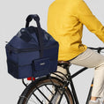 Charger l'image dans la visionneuse de la galerie, Panier vélo pour chien Oscar et Plume en bleu, fixé sur un vélo avec un cycliste portant un t-shirt jaune