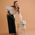 Load image into Gallery viewer, Femme souriante portant une laisse mains libres chien verte avec un dalmatien sur fond beige