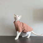 Chat portant un sweat confortable pour chat de couleur beige, debout sur une surface en bois
