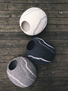 Trois cocons en laine fait main pour chat, styles modernes en différentes couleurs sur un sol en bois