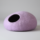 Cocon laine mérinos pour chat de couleur lavande posé sur un sol en bois clair