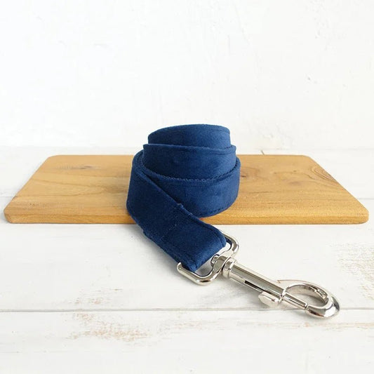 Collier personnalisable velours pour chien bleu marine avec attache métallique argentée posé sur planche en bois
