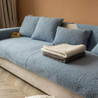 Couverture protection canapé Oscar et Plume en tissu doux bleu avec coussins assortis dans un salon moderne