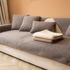 Couverture protection canapé gris en tissu doux avec coussins assortis et couvertures pliées beige et crème