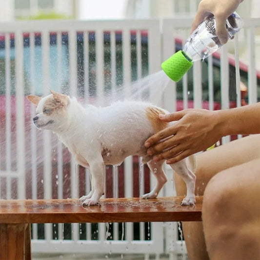 Personne utilisant une douche portable silicone chien pour laver un petit chien blanc à l'extérieur