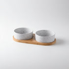 Gamelle céramique pour chien avec deux bols blancs à éclaboussures noirs sur support en bois