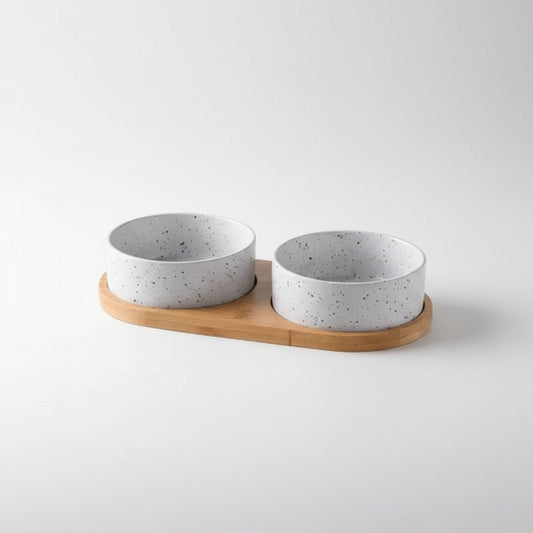 Gamelle céramique pour chien avec deux bols blancs à éclaboussures noirs sur support en bois