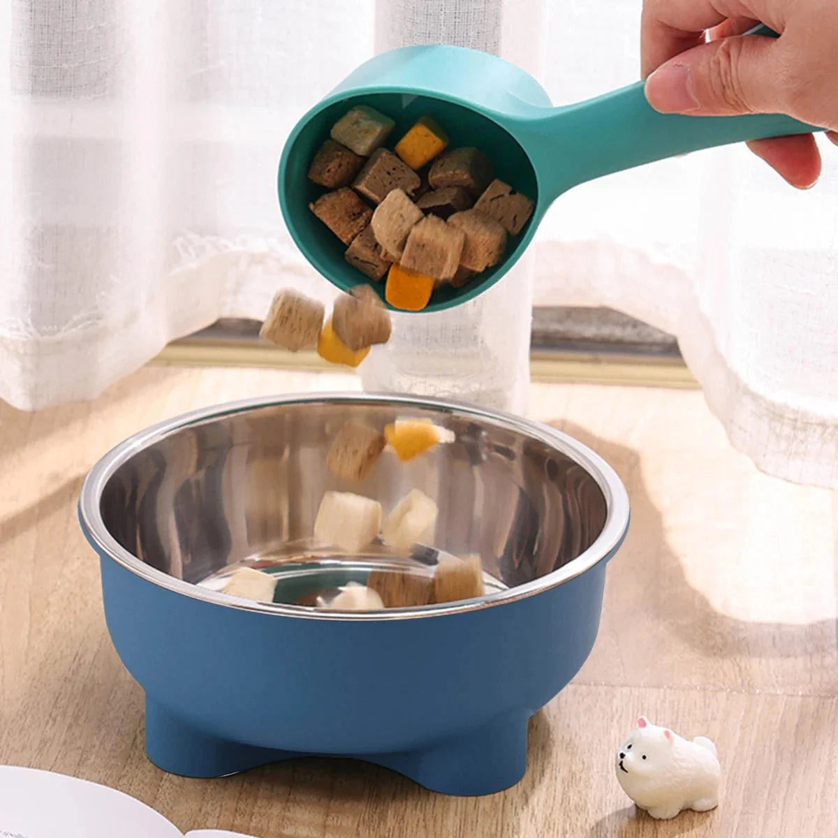 Gamelle inox pour chien bleue avec intérieur en acier inoxydable et nourriture versée avec une louche