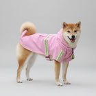 Chien Shiba Inu portant un imperméable pour chien rose avec des bandes réfléchissantes