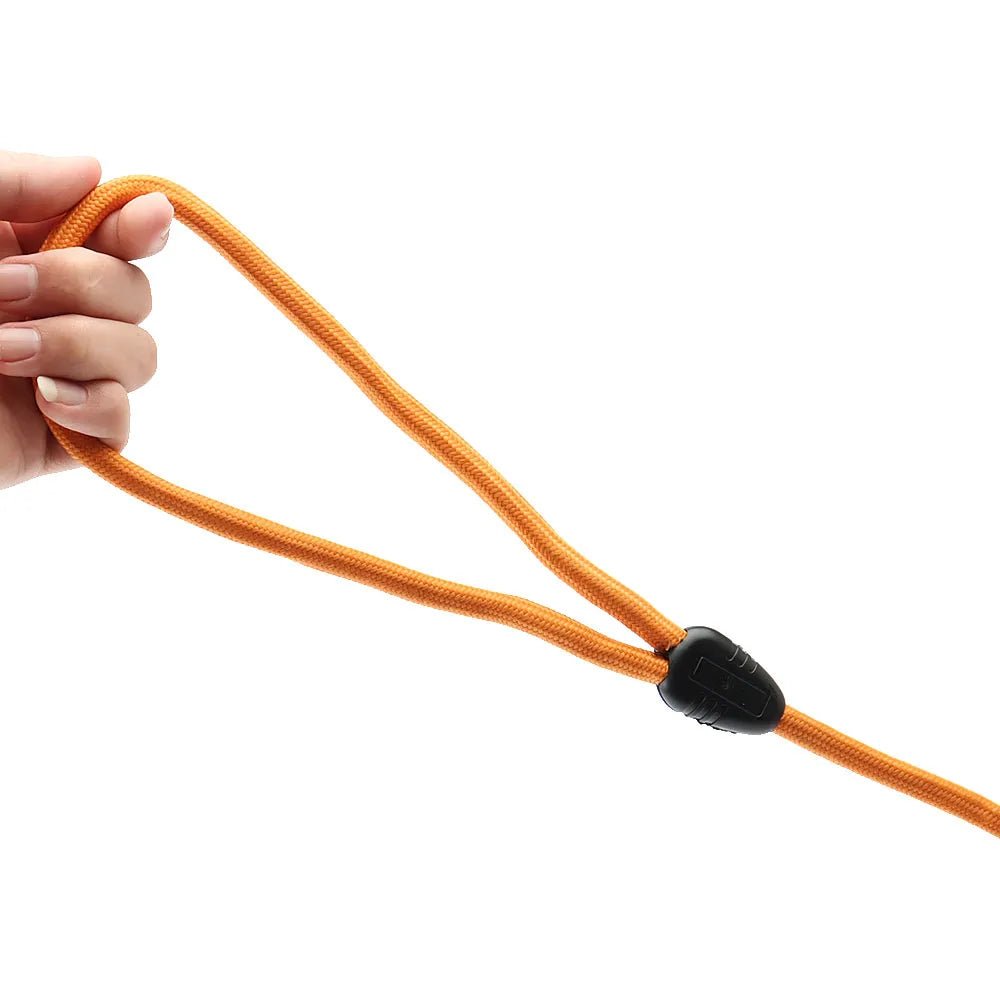 Laisse longue pour chien orange avec système de réglage noir tenue par une main