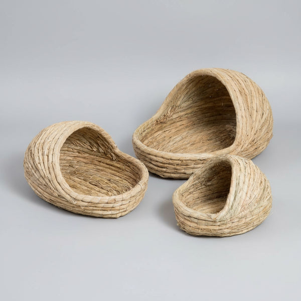 Panier chat rotin naturel de différentes tailles posé sur un sol en bois proche d'un tapis