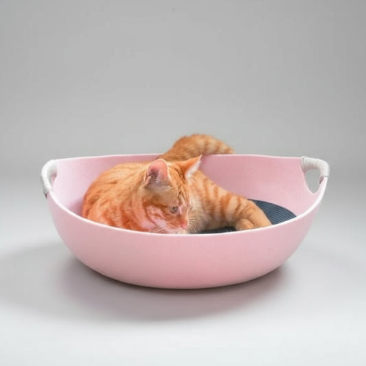 Panier feutre lavable pour chat rose avec chat roux allongé à l'intérieur dans une pièce lumineuse