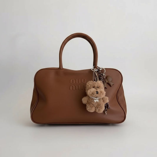 Sac à main marron orné de deux porte-clés chien peluche Oscar et Plume blanc et brun avec breloques