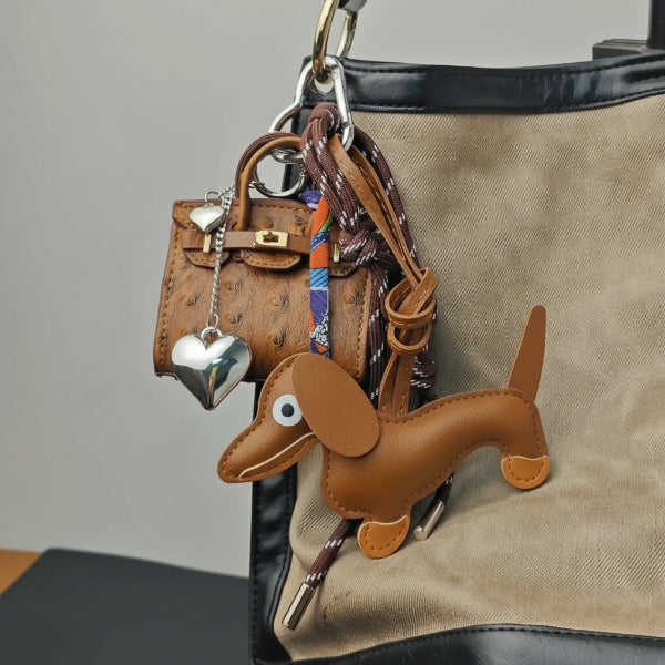 Porte-clés teckel en cuir marron accroché à un sac tendance avec d'autres accessoires