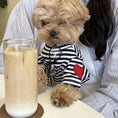 Carica l'immagine nel visualizzatore della galleria, Un chien adorable portant un t-shirt pour chien rayé avec un cœur rouge, assis à côté d'une boisson glacée
