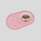 Tapis silicone gamelle chien rose avec motifs pattes et gamelle blanche remplie de croquettes