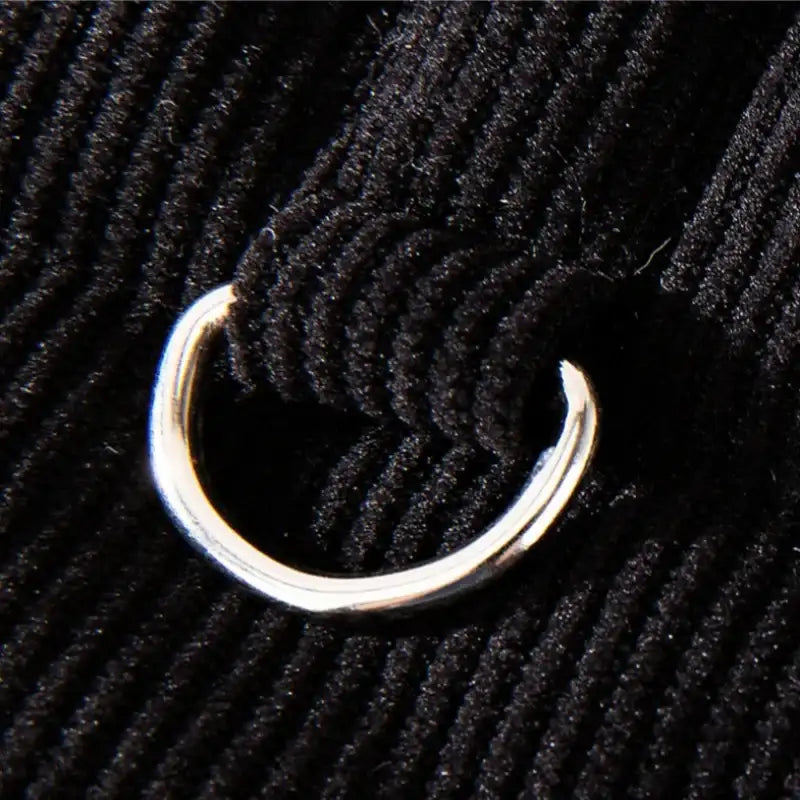 Détail en gros plan d'une boucle métallique sur manteau pour petit chien noir en tissu côtelé